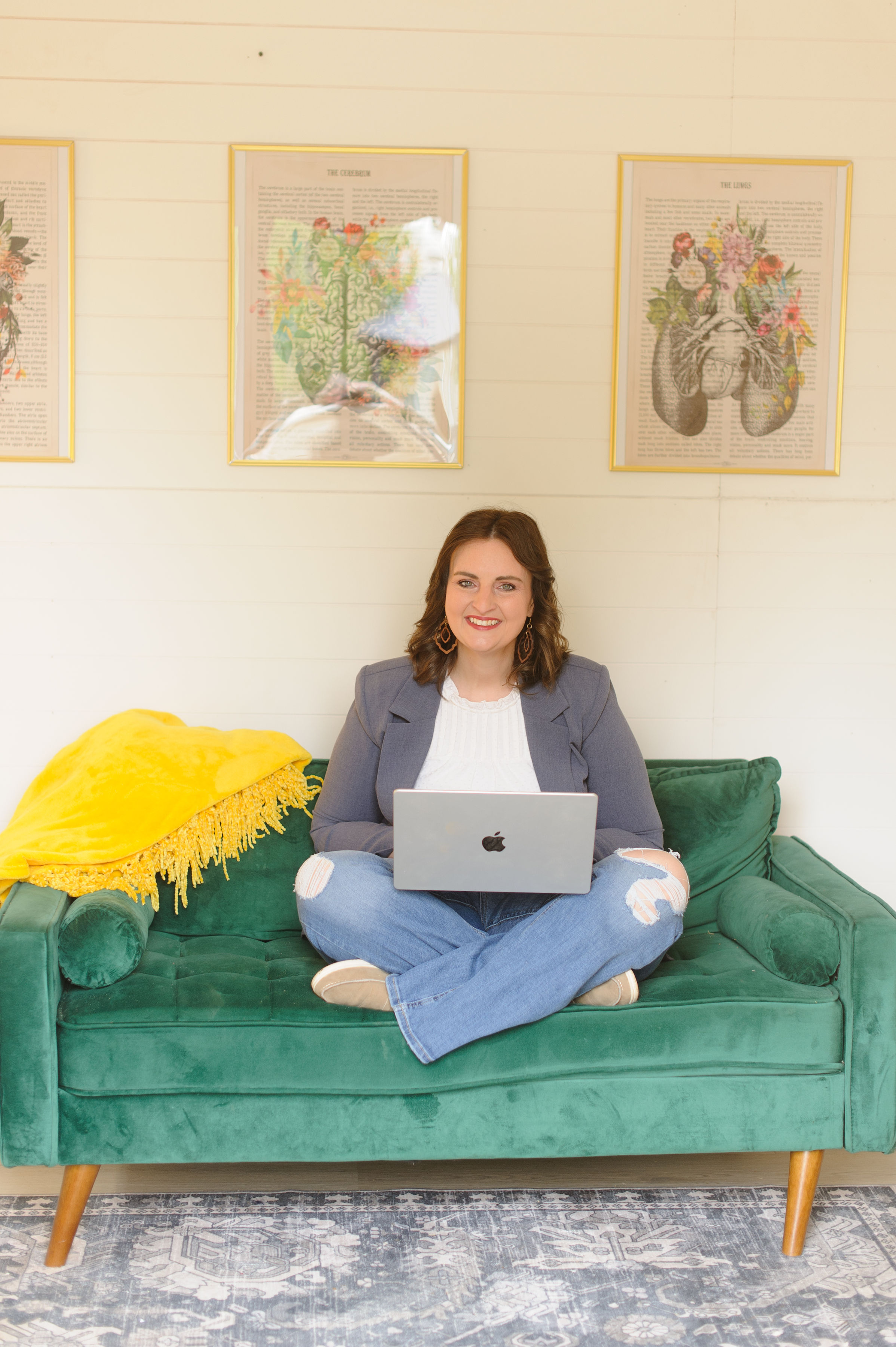 A minimal, sunlit corner of a modern living space, featuring a low, sand-colored boucle armchair with an elegantly curved back, a pale oak side table, and a single tall, leafy plant in a matte ceramic pot. On the table, a closed silver laptop and a thick, cream-colored planner are neatly stacked, suggesting focused, high-level life and leadership coaching work distinct from clinical settings. Morning light diffuses through sheer white curtains, casting soft, calming shadows. Photographic realism, composed with the rule of thirds and generous negative space, creating a serene, sophisticated mood that invites reflection and grounded ambition while evoking nervous system ease.
